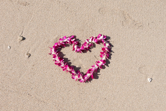 orchid flower garland necklace in love heart shape on white sand beach, romantic couple honeymoon trip at Hawaii 
