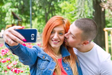 A picture of a happy couple taking selfie in the park