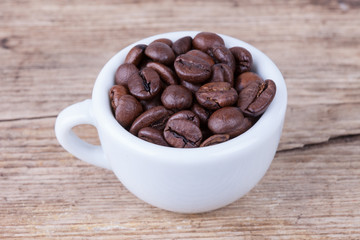 top view cup full of coffee beans on wood surface
