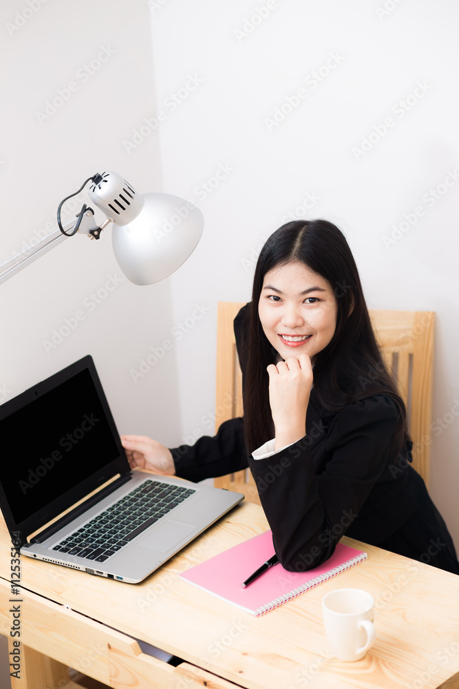 Wall mural smiling asian businesswoman with laptop computer posting in whit