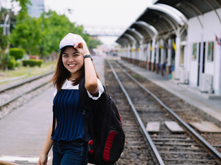 young asian girl waiting for the train in station,waiting train with smile and happy moment, single alone woman at train station with back pack for travel, filter effect