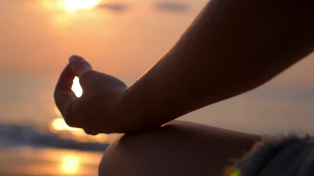 Yogi Woman Sitting in Lotus Pose Meditating at Beach at Sunset