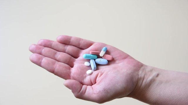 Pills pouring into an open hand. Close-up.