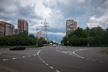 Fototapeta na wymiar Thunderclouds over houses, road and high-voltage tower in the city of Moscow