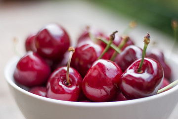 Reife Kirschen in weißer Porzellanschale, auf rustikalem Holz