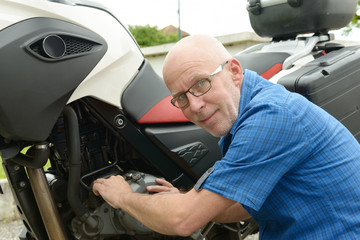 Fototapeta na wymiar senior man repairing motorbike outdoor