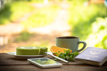Background fruit and coffee cup with green tea cake and mint with smartphone and passport.All screen about travel.On wooden background outdoor view and holiday with relax .