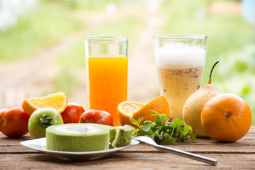 Background fruit have tomato and orange and juice with green tea cake.On wooden background outdoor view and holiday with relax .