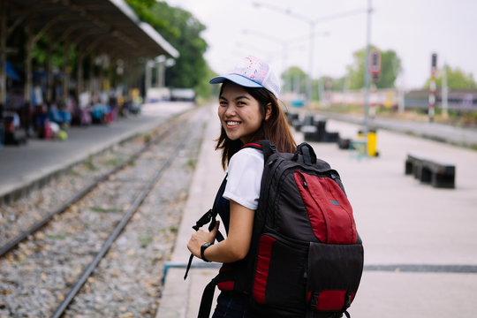 young asian girl waiting for the train in station,waiting train with smile and happy moment, single alone woman at train station with back pack for travel, filter effect