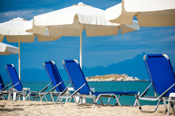 Sunshades and sunbeds on beach and blue sky