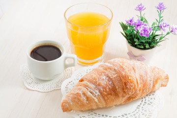 A cup of black coffee, croissant and orange juice. French breakfast