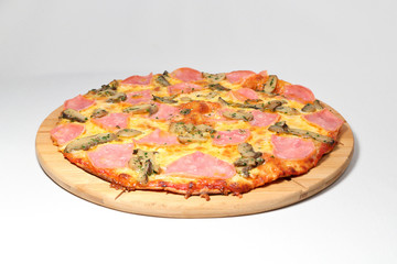 pizza with ham on a round pedestal made of wood
