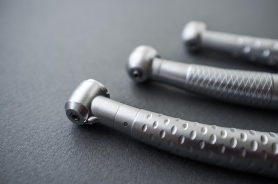 Dental turbine handpieces without burs close-up. Front view on line of three dental instruments without drills. Dental turbine handpieces without burs on gray background.