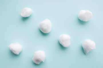 Fototapeta na wymiar Cotton balls on blue background flat lay. Several cotton balls for dentist manipulations. Close-up on group of seven cottonballs.