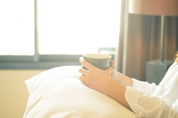 Woman hold coffee mug on the bed