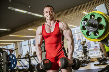 man is engaged in fitness bodybuilder posing shows biceps and smiling