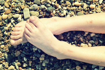 bare beautiful healthy baby feet , feet , fingers wet pebble beach a bit buried in the pebbles and sand are waiting for an excuse to escape again into the water