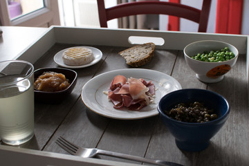 Repas naturel et sain sur un plateau dans une cuisine vintage : petits pois frais, compote de pomme, jambon cru, salade de lentille, verre de kéfir, fromage et pain 2