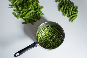 Scène de retour de marché : écossage de petits pois dans une cuisine vintage, petits pois prêts...