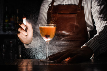 Expert barman is spraying on cocktail