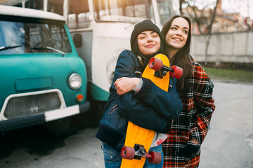 Two trendy and fashionable street girls skateboarders joking and smiling © anatoliycherkas