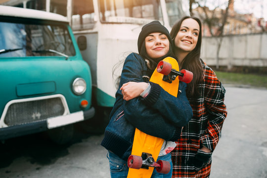 Two trendy and fashionable street girls skateboarders joking and smiling