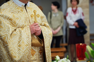 Beautiful golden cross in male hands of priest wearing gold robe