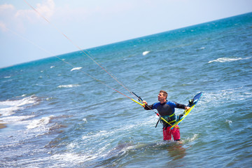 Athletic man riding on kite surf board on a sea waves