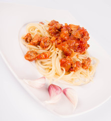 Spaghetti bolognese on a plate decorated with garlic cloves