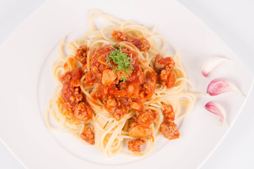 Spaghetti bolognese on a plate decorated with garlic cloves and cress