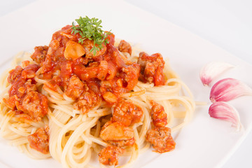 Spaghetti bolognese on a plate decorated with garlic cloves and cress