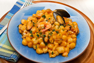 blue dish with gnocchi ,seafood and tomatoes sauce