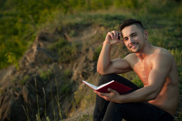 Smiling muscular man with book outdoor