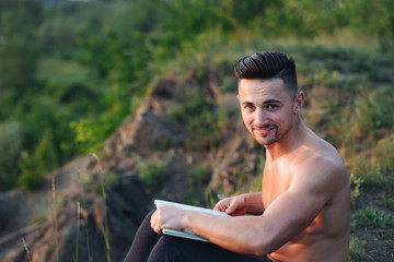 Naklejka na ściany i meble Smiling muscular man with laptop outdoor