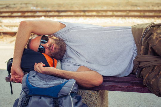 Male backpacker tourist napping on a bench