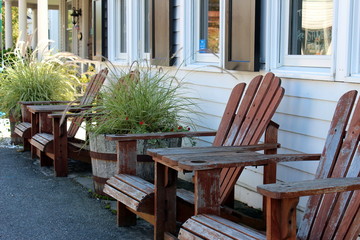 red adirondack chairs lined up against a building with plants in half barrels