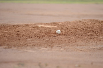 Baseball sitting on the pitching mound dirt.