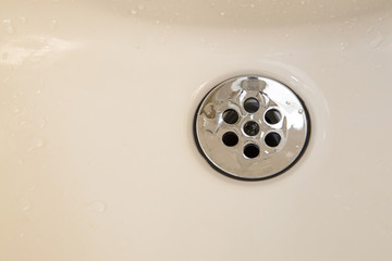 Standard round drain hole in white domestic sink.