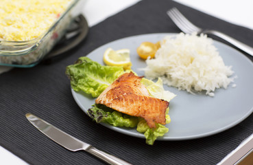 Fish atlantic salmon with salad and grated radish. The main meal for dinner with fish on the blue plate.