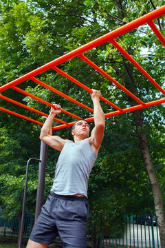 Muscular man doing pull-ups on horizontal bar
