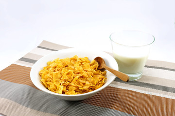 cornflakes with a cup of milk on colorful table mat