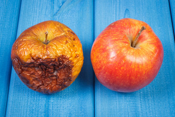 Old wrinkled and fresh apples on blue boards