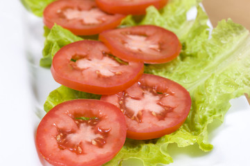 Sliced tomatoes on leaves of lettuce.