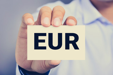 EUR letters (EURO currency code) on the card shown by a man