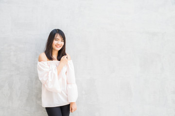 Happy young woman against concrete wall.
