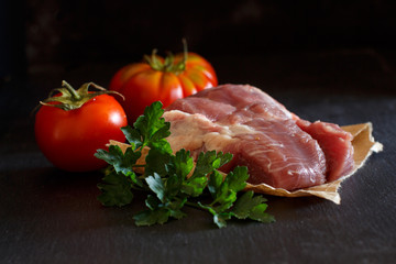 Slice of raw turkey steak with herbs and tomatoes