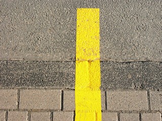 Ablösbare gelbe Fahrbahnmarkierung auf grauen Asphalt und Straßenpflaster der Bürgersteig mit...