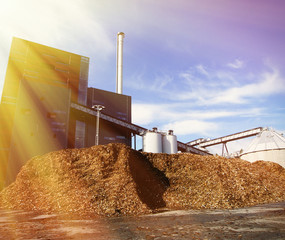 bio power plant with storage of wooden fuel against blue sky