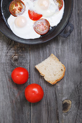 Omelette with tomato in frypan on rustic gray wooden background