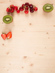 Orange, kiwi, cherry, strawberry on a wooden background
